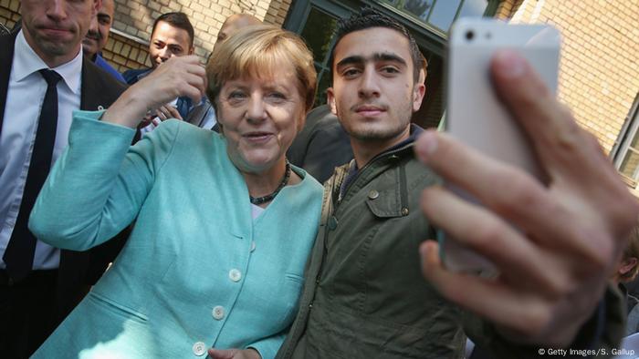 Un réfugié syrien prenant un selfie avec Angela Merkel en 2015 