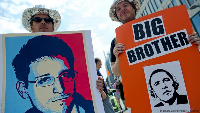 Protesters hold posters with a portrait of Edward Snowden