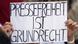 A protester in Berlin holding a sign that says: "Press freedom is a fundamental right" A protester in Berlin holding a sign that says: "Press freedom is a fundamental right"