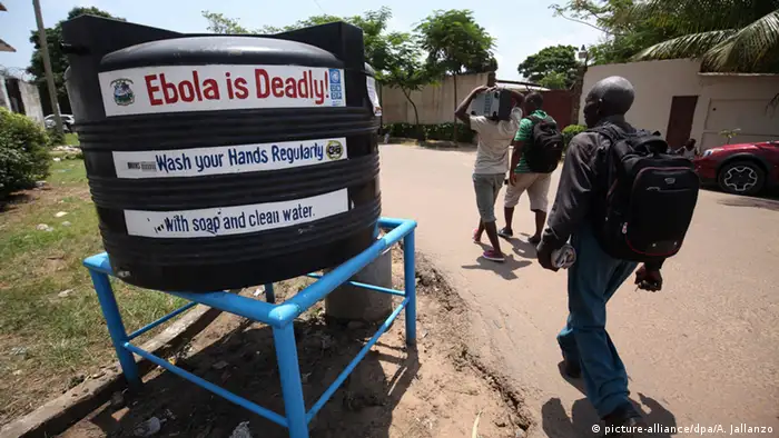 A man walks past a water tank that warns 'Ebola is deadly'
