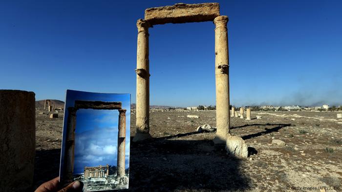 A picture taken on March 31, 2016 shows a photographer holding his picture of the Temple of Baal Shamin seen through two Corinthian columns (Getty Images/AFP/J. Eid)