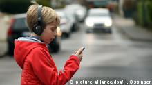 Deutschland Junge mit Smartphone im Straßenverkehr