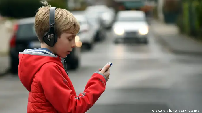 Deutschland Junge mit Smartphone im Straßenverkehr