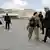 Kerry strides across the airport in Kabul, talking to a US army soldier.