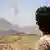 A soldier loyal to Yemeni President Hadi watches smoke rise in the distance on Sunday, just hours before a UN-backed ceasefire was to take effect.