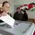Сирийка опускает бюллетень в урну на избирательном участке