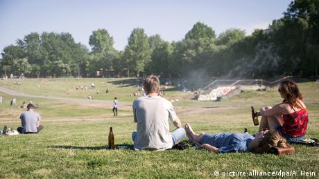 People drinking beer as they sit on a grassy field 