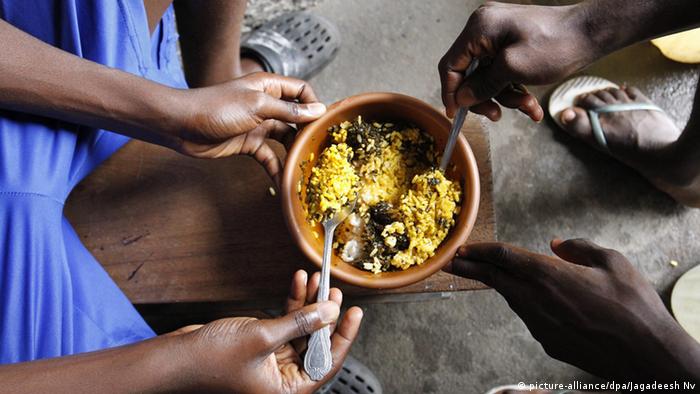 Two Liberians eating rice out of a bowl