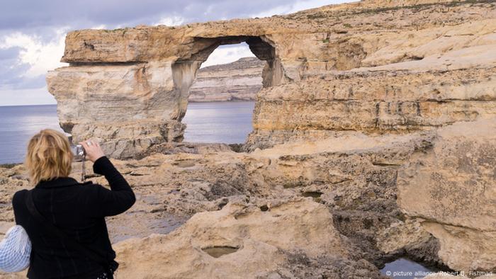 A tourist takes a photo of the Azure Window rock arch on Malta. 