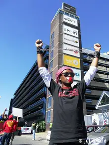 A person lifts their arms in protest in front of a building