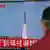 A man watches a TV news showing file footage of a North Korean missile launch