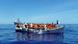 Migrants sit in their small boat as an Italian navy ship approaches to rescue them. Migrants sit in their small boat as an Italian navy ship approaches to rescue them.