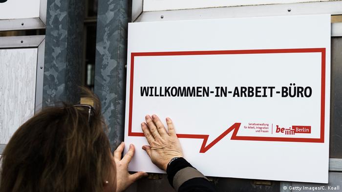 Deutschland Berlin Christiana Hansen hängt Schild für Jobsuchende Flüchtlinge auf