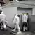 Männer in weißen Anzügen an einer Garage 2014 (Foto: dpa)
