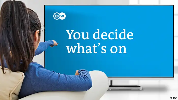 A woman is sitting in front of a TV screen that shows the words You decide what's on and the DW logo.
