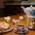 Teetasse, Kanne, Milchkännchen, Würfelzucker, eine Kerze und Waffeln mit Sahne auf einem Tisch