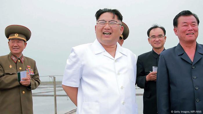 Lachender Kim Jong Un im Hemd mit Gefährten (einer in Uniform) Foto: Getty Images/AFP/KNS)