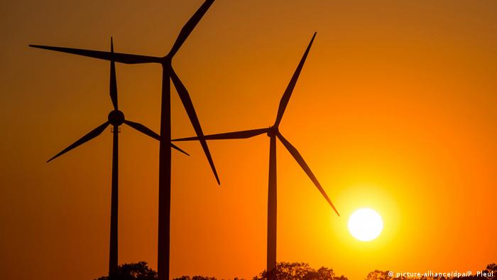 Windturbines stand still against a backdrop of a setting sun