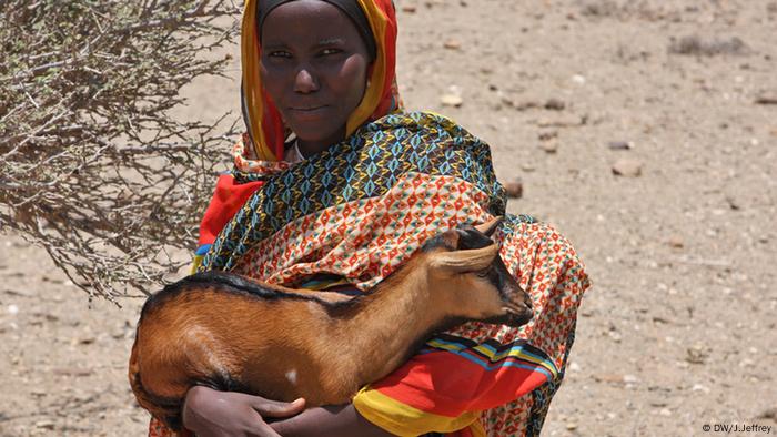 A colorful pastoralist carrying a goat 