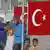 Беженцы за забором, на котором закреплен флаг Турции