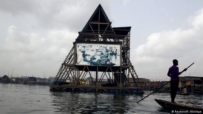 A-shaped Makoko Floating School building on water, with man on boat to the right