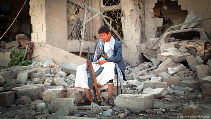 An armed Yemeni youth, loyal to the Shiite Muslim Huthi movement that controls Sanaa, sits amid the rubble on December 5, 2014, guarding the damaged house of the Iranian ambassador