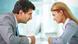 A man and a woman in office suits looking sternly at each other. A man and a woman in office suits looking sternly at each other.