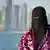 A Saudi woman with the skyline of Qatar's Doha behind her