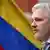 Julian Assange with an Ecuadorian flag in the background