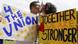 A man holding a sign, "4 the Union" kisses woman holding a sign "Together we are stronger," as the spire of teh Big Ben clock tower rises behind them. A man holding a sign, "4 the Union" kisses woman holding a sign "Together we are stronger," as the spire of teh Big Ben clock tower rises behind them.