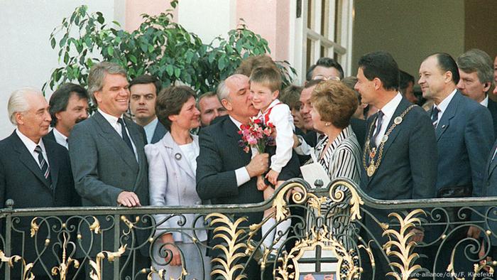 Gorbachev kissing a child on the balcony of the Alten Rathaus in Bonn amid onlooking political colleagues and his wife, Raissa