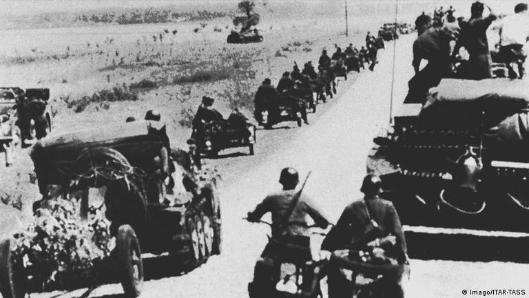A black and white photo of German troops in vehicles on a road