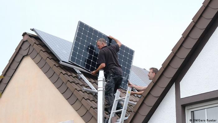Handwerker montieren Solarpanelen auf einem Hausdach in Köln. Das Haus wurde dank der Photovoltaik zum Energie-Plus-Haus. 