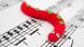 Un gusano rojo de tela sobre una partitura. Un gusano rojo de tela sobre una partitura.