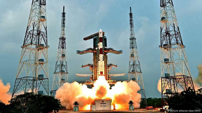 Smoke and flames burst from the base of a rocket as it lifts off into space