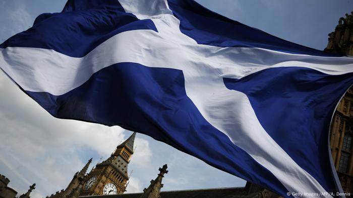 A member of public flies a giant Scottish Saltire flag outside the Houses of Parliament in London