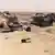 Сгоревшие машины и разбросанные предметы после авианалета на позиции ИГ