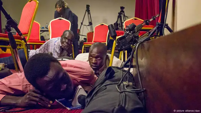 Several people lie on carpet looking shocked