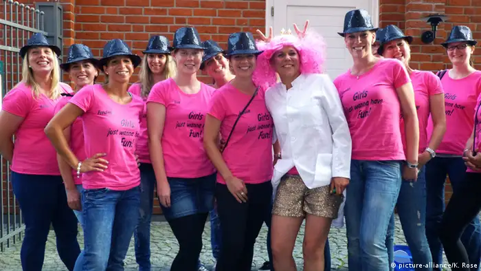 Mehrere Frauen im rosa T-Shirt stehen neben einer Frau mir rosa Perücke und Hörnern