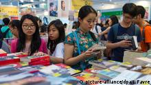 20.07.2016 epa05433042 Visitors read books at the 27th Hong Kong Book Fair in the Exhibition and Convention Centre in Wanchai, Hong Kong, China, 20 July 2016. The seven-day fair features 640 exhibitors and is expected to attract more than a million people. EPA/JEROME FAVRE | Copyright: picture-alliance/dpa/J. Favre