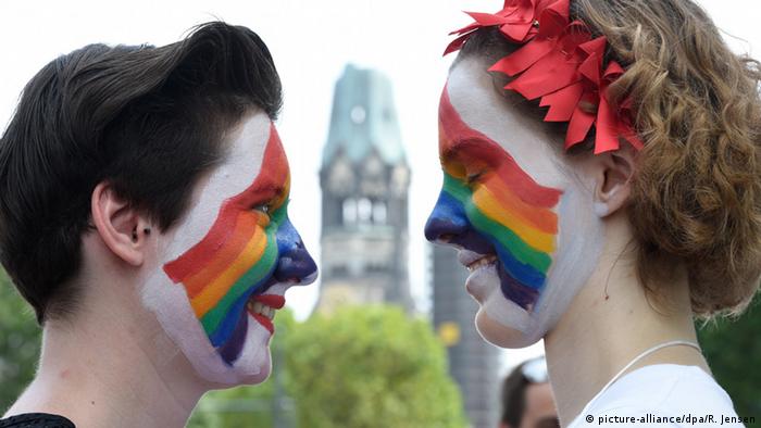 Two people with rainbow-painted faces at the Christopher Street Day in Berlin
