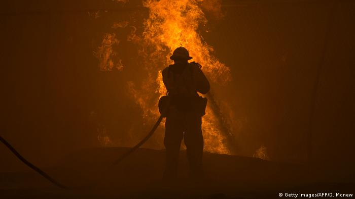 Ein Feuerwehrmann bekämpft die Flammen eines Waldbrands in Kalifornien mit einem Feuerwehrschlauch in der Hand (Foto: Getty Images/AFP/D. Mcnew).