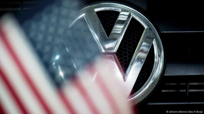 El emblema de Volkswagen junto a una bandera estadounidense. 
