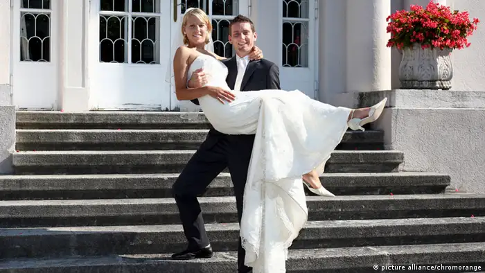 Ein Mann trägt seine Braut die Treppe hoch 