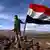 Солдат сирийского правительства с флагом Сирии