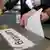 A hand drops a ballot into a box