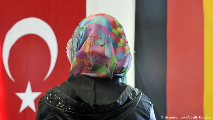 Deutschland Friedberg Frau mit Kopftuch vor türkischer und deutscher Fahne