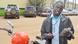 Motorbike taxi driver Mwanje Bernard holds a smartphone, standing in front of his motorcycle. Motorbike taxi driver Mwanje Bernard holds a smartphone, standing in front of his motorcycle.