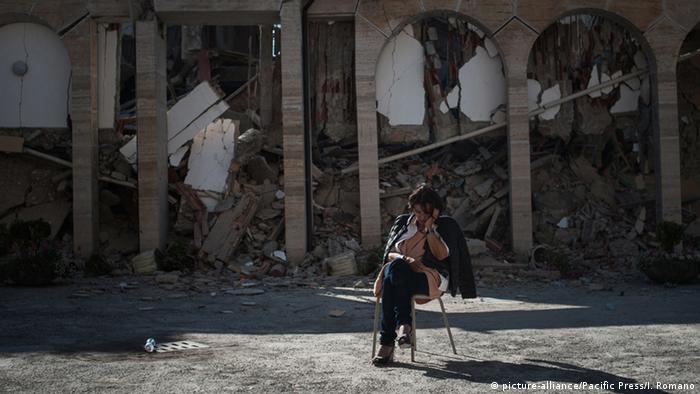 Плачущая женщина на фоне развалин