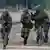 Uniformierte Bundeswehr-Soldaten laufen mit Waffen (Foto: picture-alliance/dpa/S. Sauer)